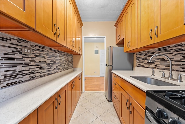 kitchen with sink, appliances with stainless steel finishes, tasteful backsplash, a textured ceiling, and light tile patterned flooring