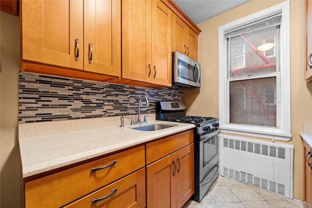 kitchen with radiator, light tile patterned floors, sink, appliances with stainless steel finishes, and backsplash