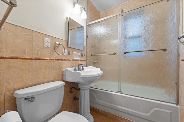 bathroom with tile patterned flooring, enclosed tub / shower combo, tile walls, and toilet