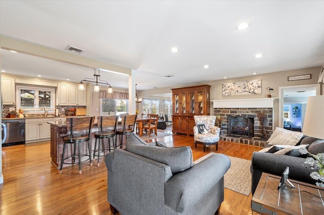 living room with sink, a fireplace, and light hardwood / wood-style floors