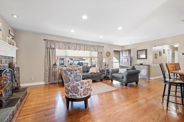 living room featuring a stone fireplace and light hardwood / wood-style floors