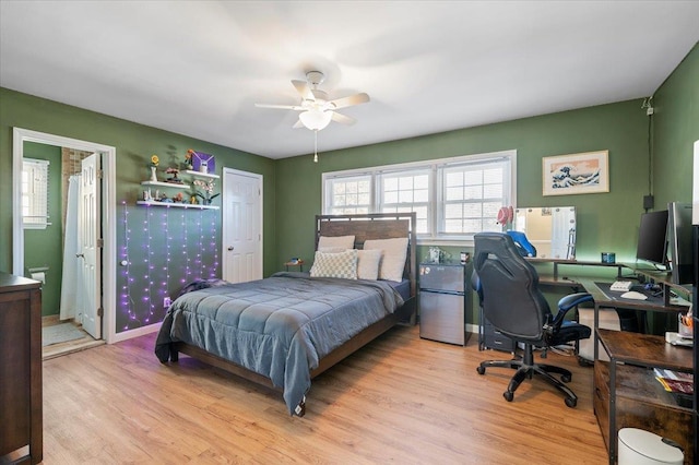 bedroom with ceiling fan, connected bathroom, stainless steel fridge, and light wood-type flooring