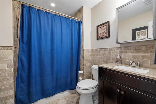 bathroom featuring curtained shower, tile walls, tile patterned flooring, vanity, and toilet