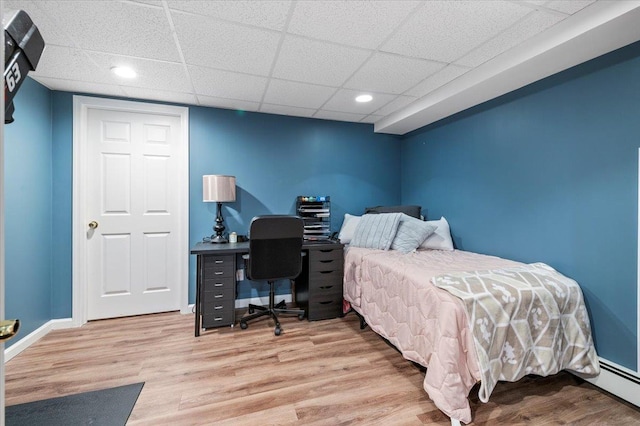 bedroom featuring hardwood / wood-style floors, a baseboard radiator, and a paneled ceiling