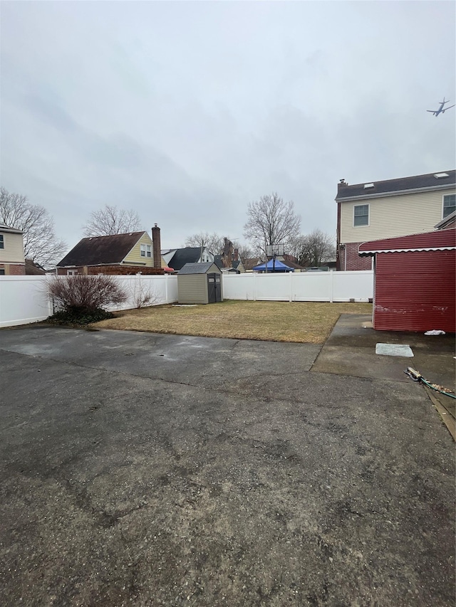 view of yard featuring a storage shed, an outdoor structure, and a fenced backyard