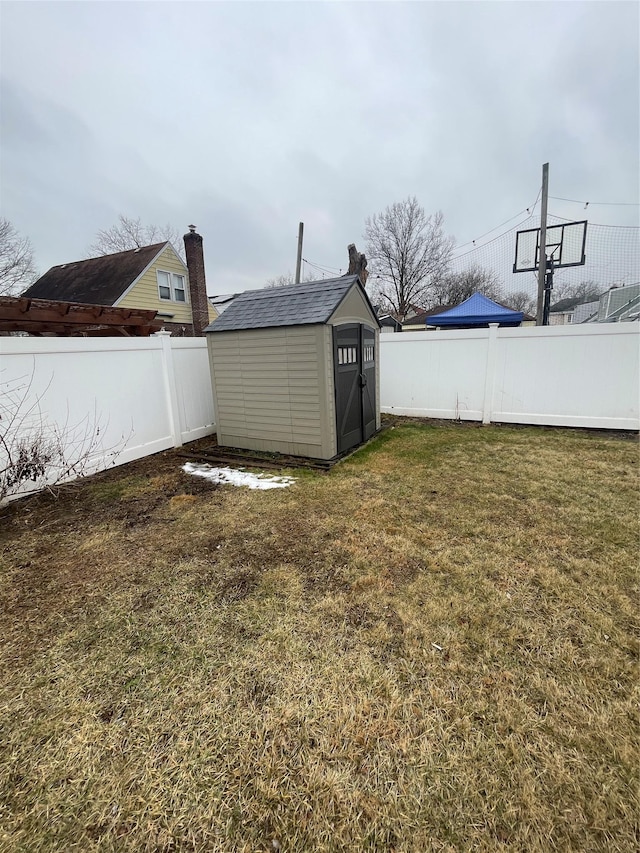 view of yard featuring a fenced backyard, a storage unit, and an outbuilding