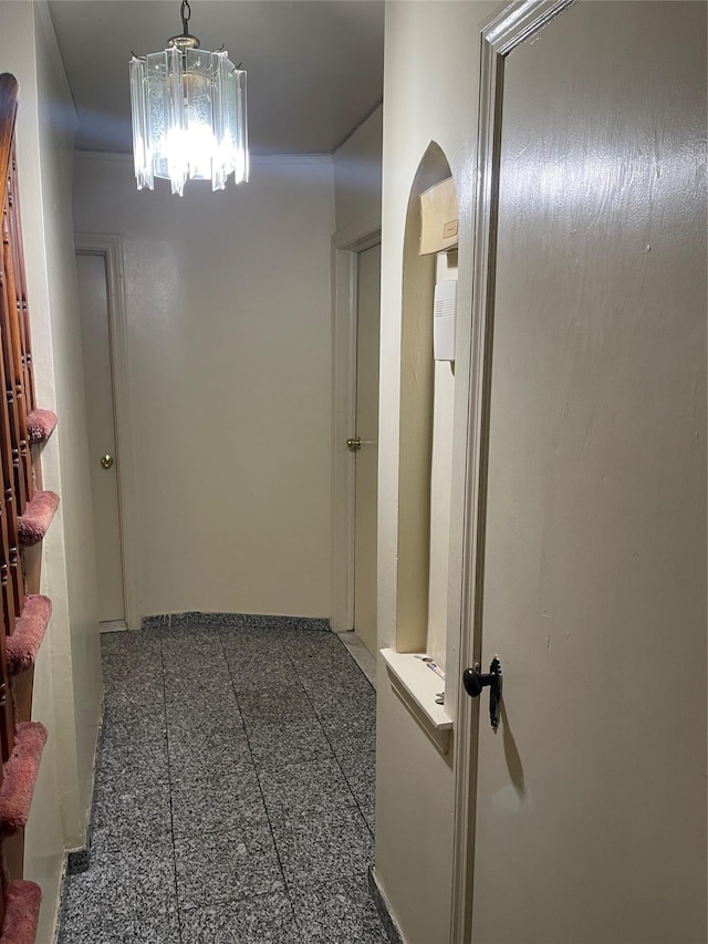 hall with arched walkways, granite finish floor, and a notable chandelier