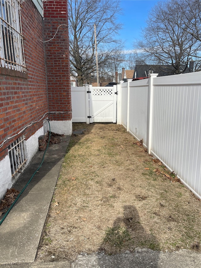 view of yard with a fenced backyard and a gate