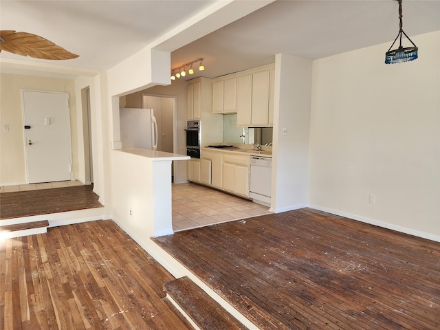 kitchen featuring rail lighting, white cabinetry, light wood-type flooring, pendant lighting, and white appliances