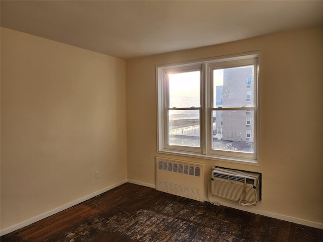 spare room featuring a wall mounted AC, dark hardwood / wood-style floors, and radiator