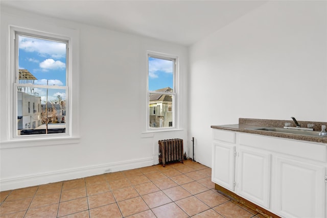 unfurnished dining area with light tile patterned flooring, radiator, and sink