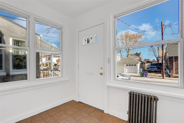 doorway to outside with radiator heating unit, light parquet flooring, and plenty of natural light