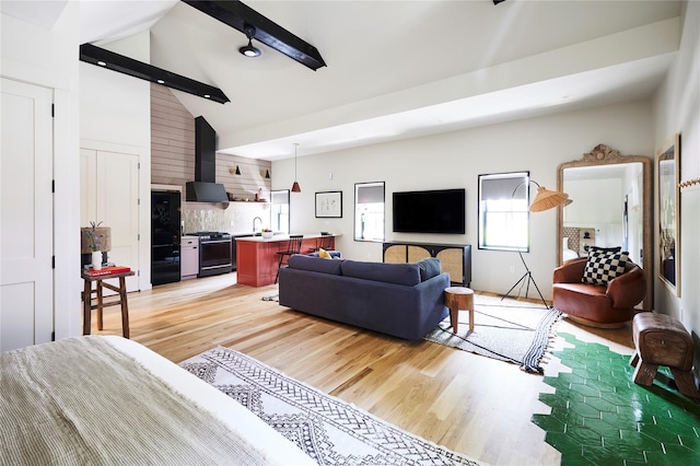 living room featuring high vaulted ceiling, beam ceiling, light hardwood / wood-style floors, and sink