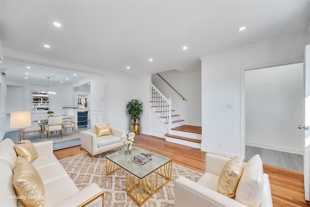 living room with a notable chandelier, crown molding, beverage cooler, and light hardwood / wood-style floors