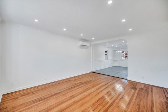 spare room with ornamental molding, a wall unit AC, and light hardwood / wood-style flooring