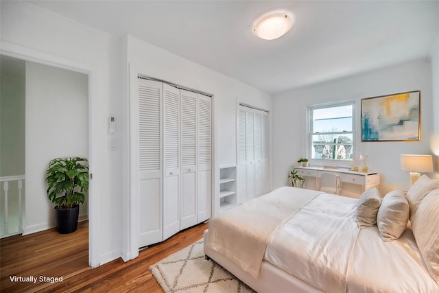 bedroom with hardwood / wood-style flooring and two closets