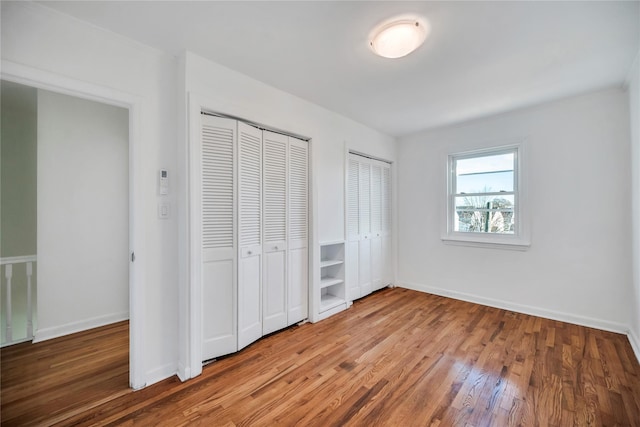 unfurnished bedroom featuring hardwood / wood-style flooring and two closets