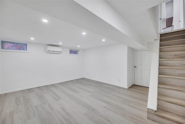 basement featuring light wood-type flooring and a wall unit AC