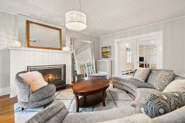 living room with hardwood / wood-style flooring, a baseboard radiator, a brick fireplace, and ornamental molding