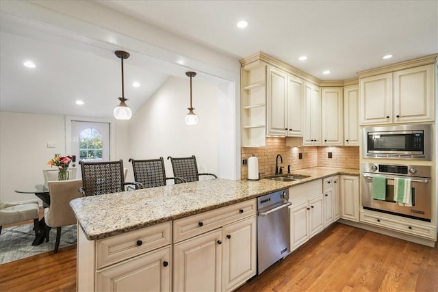 kitchen featuring hanging light fixtures, appliances with stainless steel finishes, sink, and kitchen peninsula