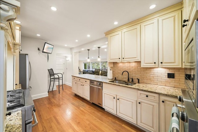 kitchen featuring decorative light fixtures, sink, decorative backsplash, cream cabinets, and light hardwood / wood-style flooring