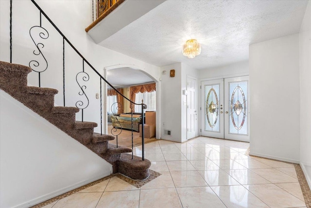 entrance foyer with light tile patterned flooring, a textured ceiling, and french doors