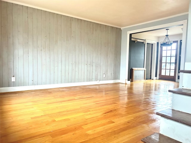 unfurnished room with ornamental molding, a barn door, and hardwood / wood-style floors