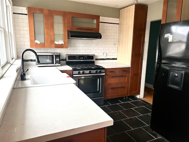 kitchen featuring appliances with stainless steel finishes, ventilation hood, sink, dark tile patterned flooring, and decorative backsplash