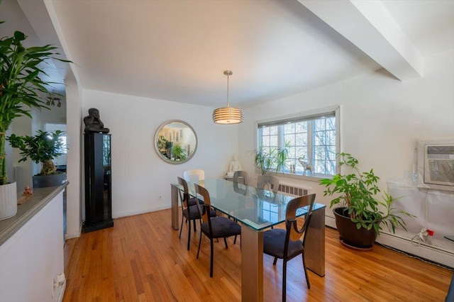 dining room with beamed ceiling, a baseboard radiator, an AC wall unit, and light hardwood / wood-style flooring