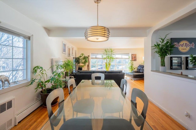 dining space featuring a baseboard heating unit, a wealth of natural light, and light hardwood / wood-style flooring