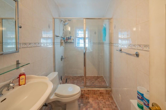 bathroom featuring tile walls, sink, a shower with shower door, and toilet