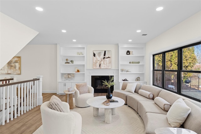 living room featuring built in shelves and light wood-type flooring