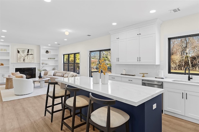 kitchen featuring sink, light hardwood / wood-style flooring, a kitchen breakfast bar, a center island, and white cabinets