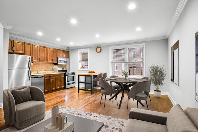 kitchen featuring decorative backsplash, appliances with stainless steel finishes, light hardwood / wood-style flooring, and ornamental molding