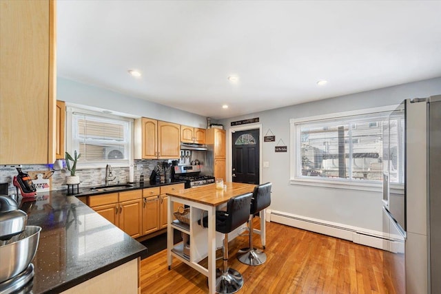 kitchen with stainless steel range with gas cooktop, sink, baseboard heating, and light hardwood / wood-style floors