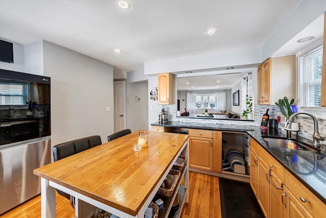 kitchen featuring sink, backsplash, light hardwood / wood-style floors, and kitchen peninsula