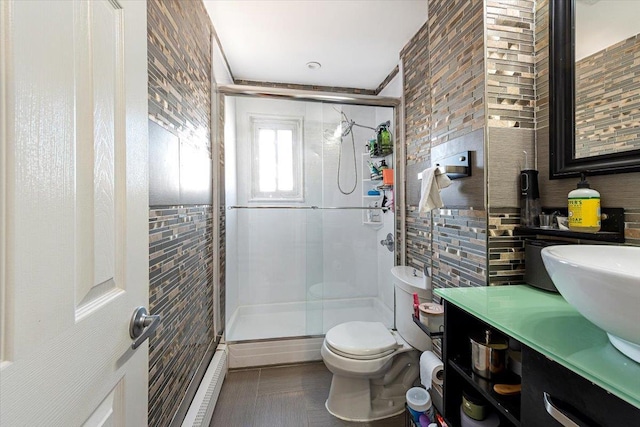 bathroom featuring vanity, toilet, a shower with door, and tile walls