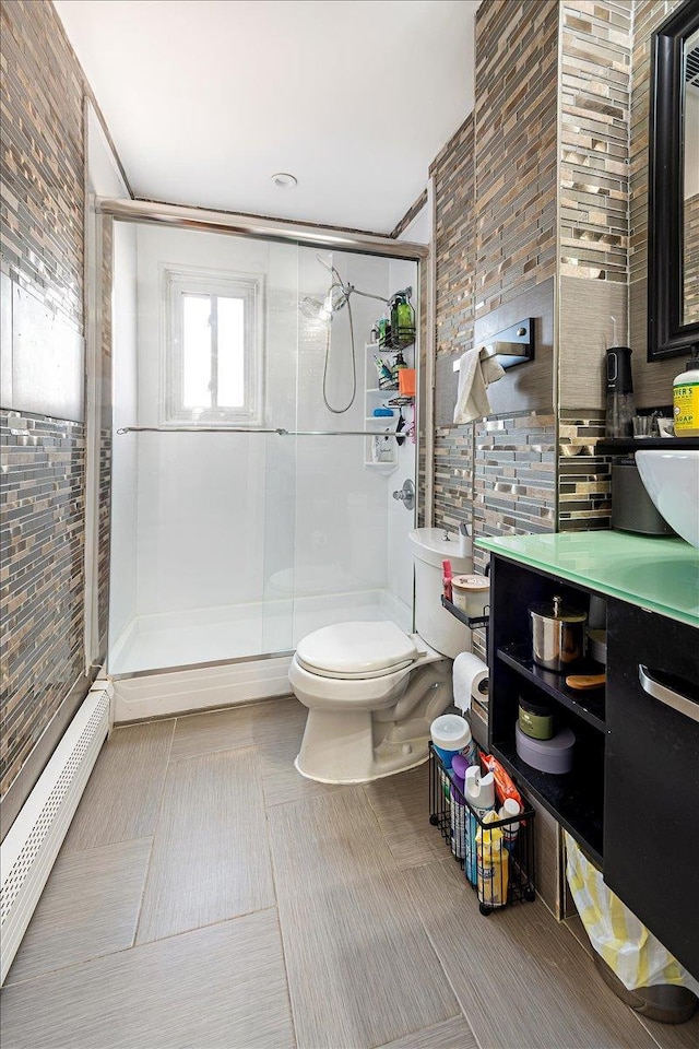 bathroom featuring vanity, toilet, a shower with shower door, and a baseboard heating unit