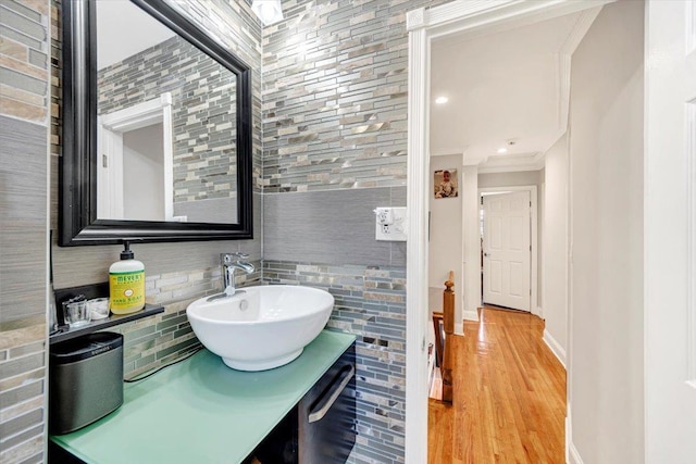 bathroom featuring vanity, crown molding, decorative backsplash, and hardwood / wood-style flooring