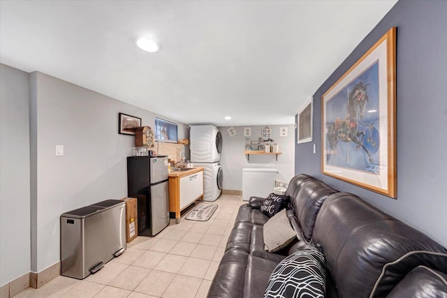 living room featuring light tile patterned floors, sink, and stacked washer / dryer