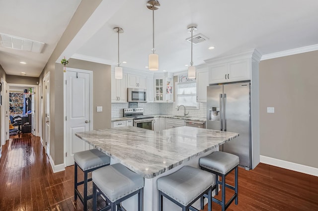 kitchen featuring hanging light fixtures, white cabinetry, appliances with stainless steel finishes, and a kitchen island