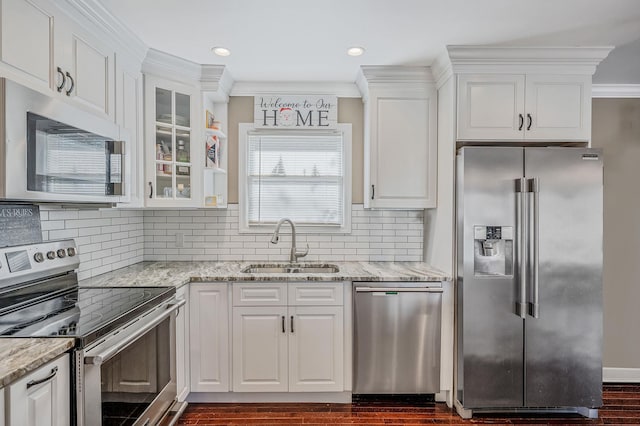 kitchen featuring sink, white cabinetry, ornamental molding, stainless steel appliances, and light stone countertops