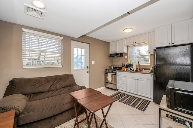 kitchen featuring white cabinets, sink, light tile patterned floors, and black appliances