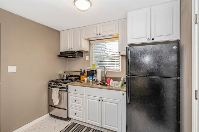 kitchen with stainless steel stove, white cabinetry, sink, light tile patterned floors, and black fridge