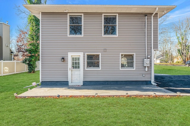 rear view of house featuring a wooden deck, a patio area, and a lawn