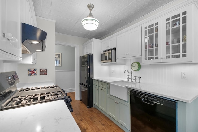 kitchen with decorative light fixtures, sink, exhaust hood, light hardwood / wood-style floors, and black appliances