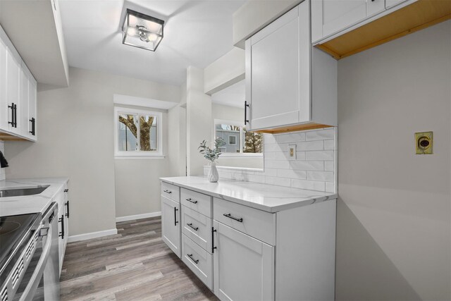 kitchen featuring light stone countertops, tasteful backsplash, white cabinetry, and light wood-style flooring