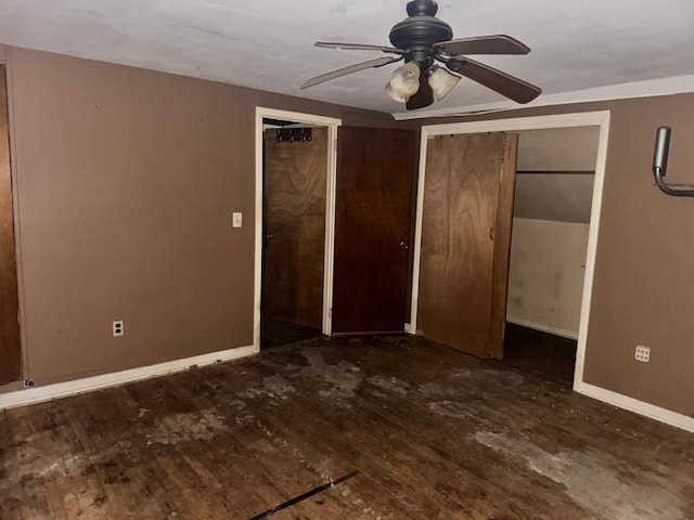 unfurnished bedroom with two closets, dark hardwood / wood-style floors, and ceiling fan