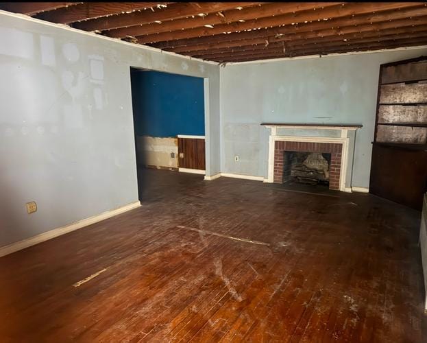 unfurnished living room with dark hardwood / wood-style flooring and a brick fireplace