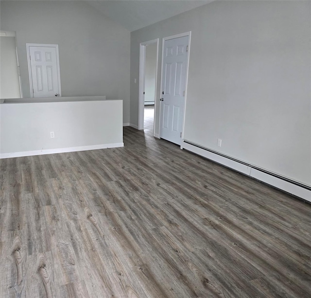 unfurnished room with a baseboard heating unit, dark wood-type flooring, and vaulted ceiling